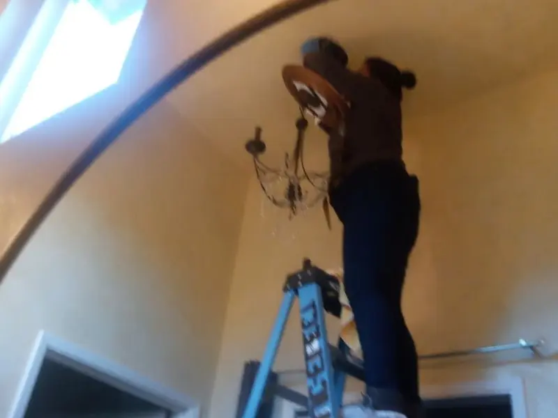 Electrician installing a chandelier in a Buda residence